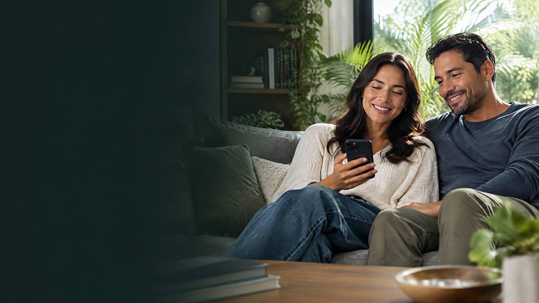 Pareja hispana sonriendo mientras revisa su teléfono en casa